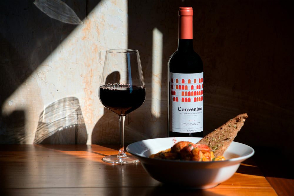 Guida pratica all'abbinamento cibo-vino con bottiglia di vino, calice e piatto