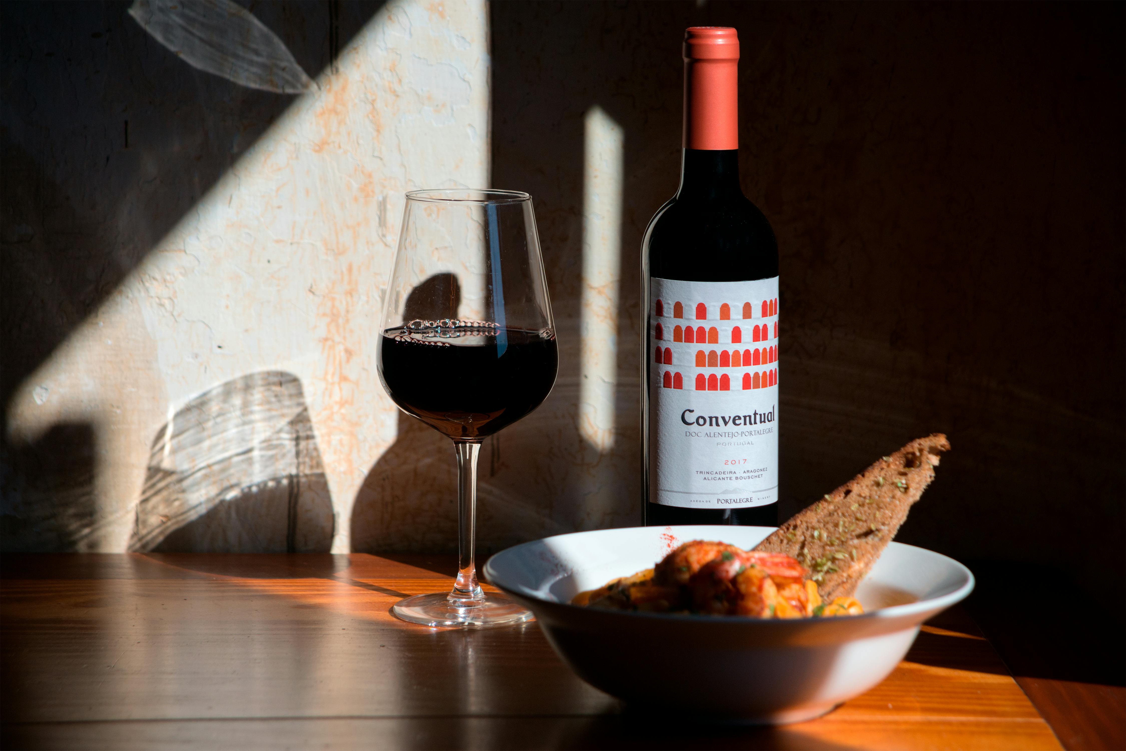Guida pratica all'abbinamento cibo-vino con bottiglia di vino, calice e piatto