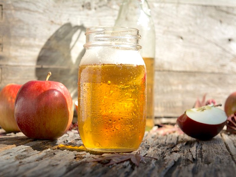 Bicchieri di sidro di mele frizzante con mele fresche sullo sfondo